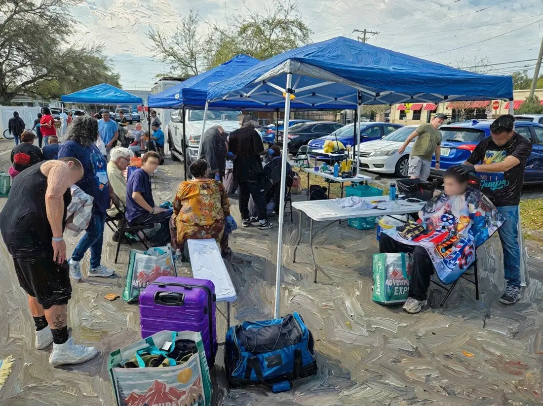 Volunteers giving haircuts to neighbors seated under blue pop-up tents at an outdoor Tampa Bay outreach event, with tables of supplies alongside